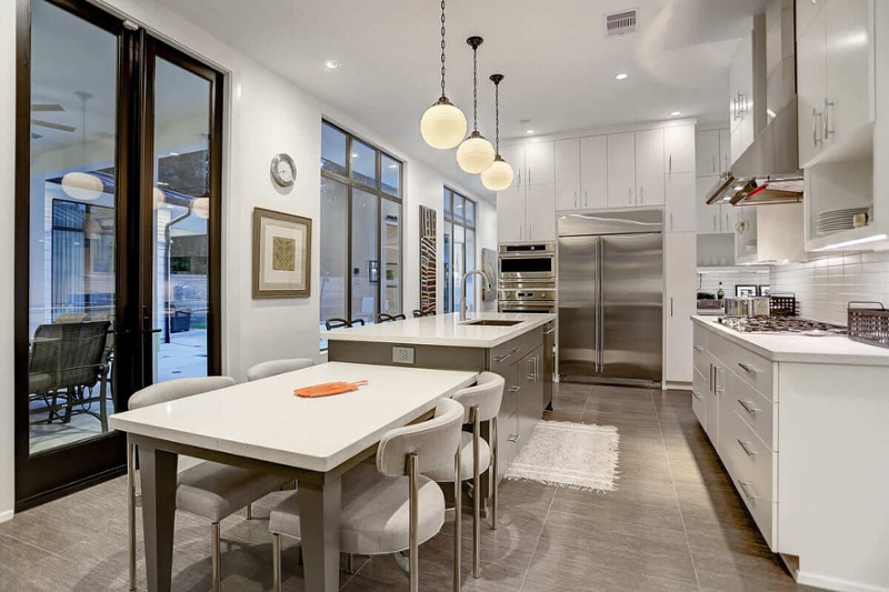 Open concept kitchen with steel appliances and white cabinets.